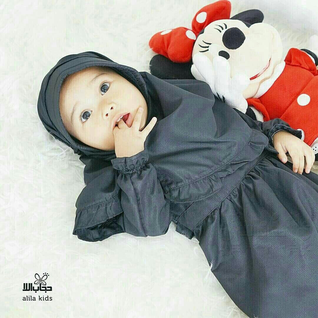 a doll laying on a bed with a stuffed animal